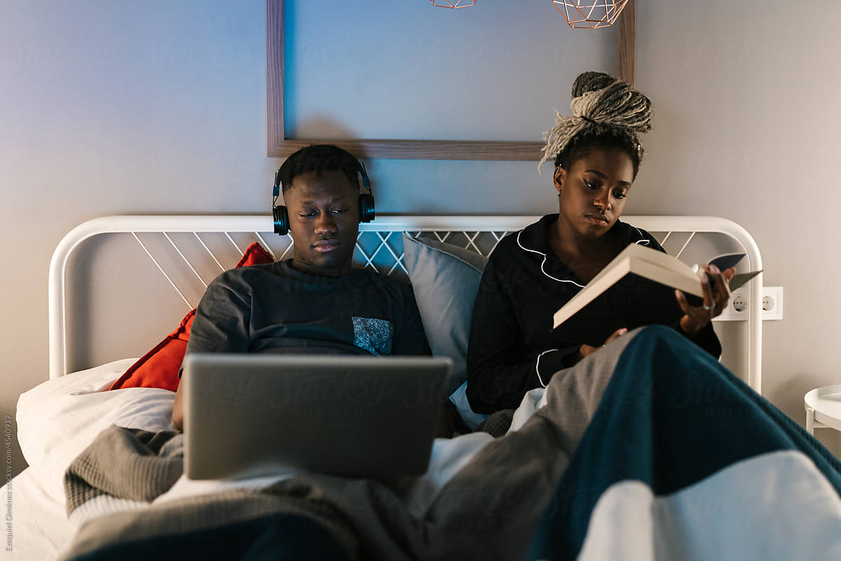 Couple watching film and reading book