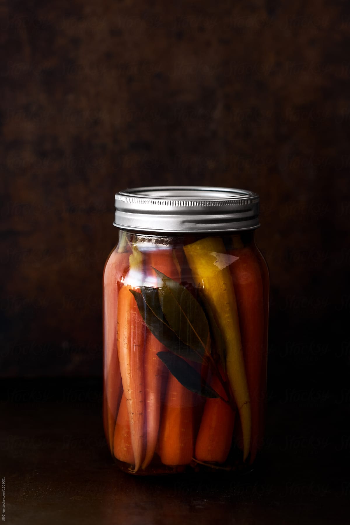 Jar of pickled carrots on dark background