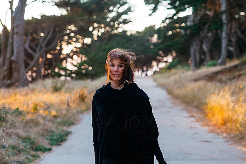 young female woman walks down path on adventure near coast during sunset