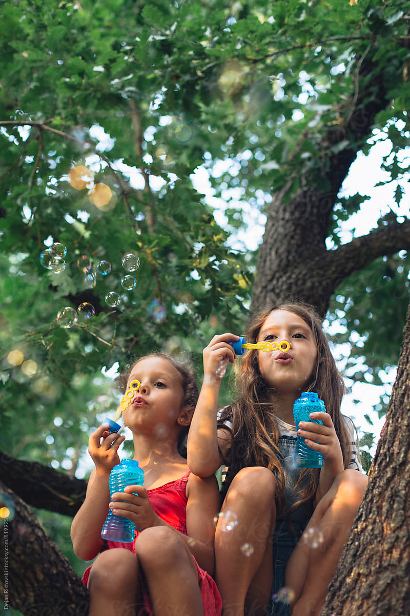 Girls on a tree blowing bubbles.