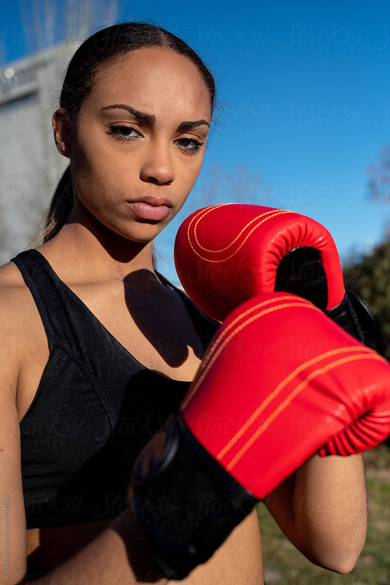 Serious female boxer in gloves in park