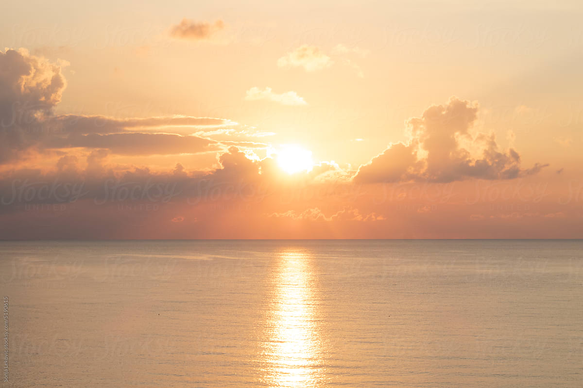 pastel orange and yellow sea water surface and sky at sunset