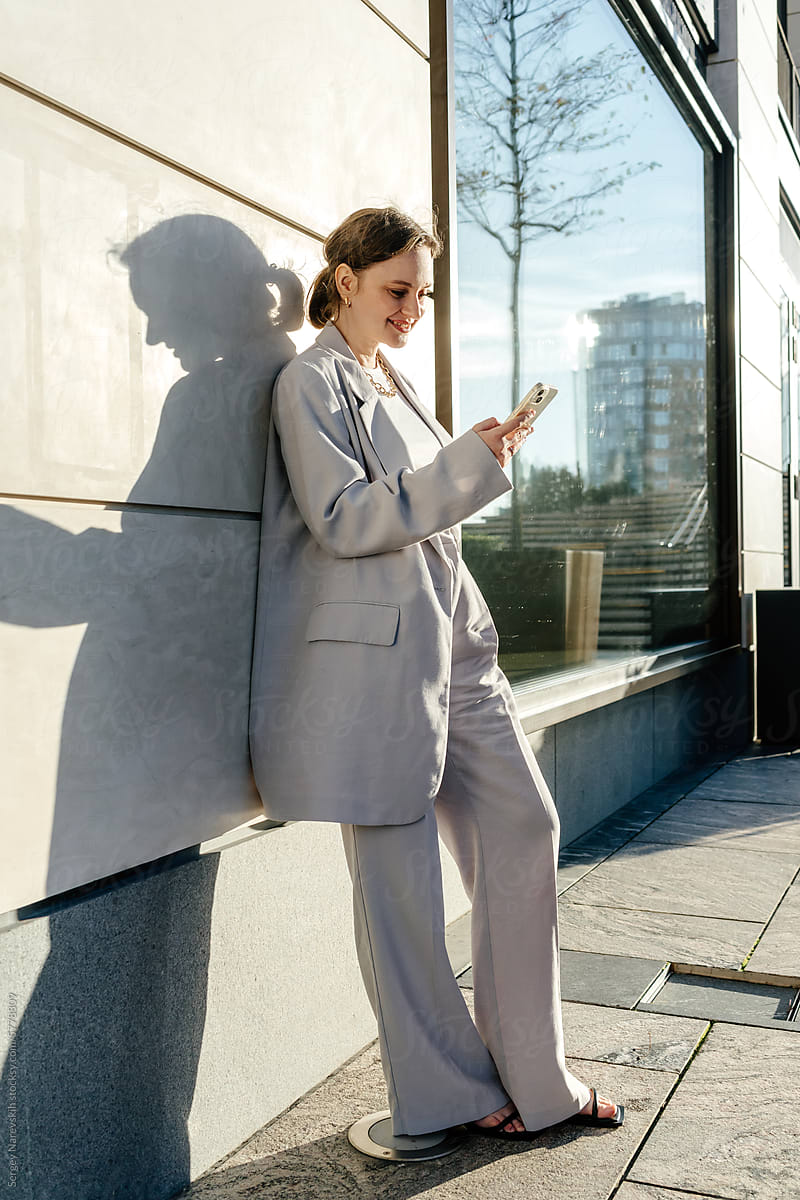 Woman browsing smartphone in sunlight, shadow and light
