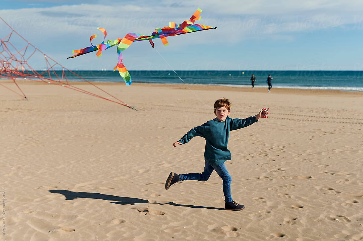 Boy running on a beach with a kite