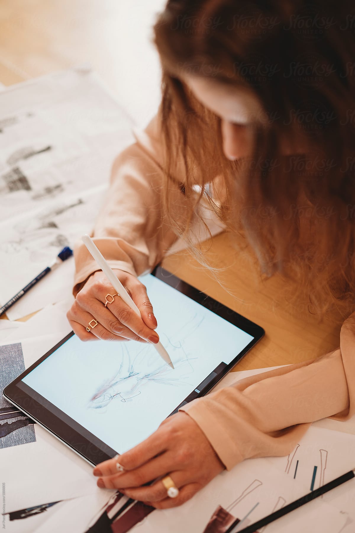 Young female fashion designer uses her tablet to make fashion sketches