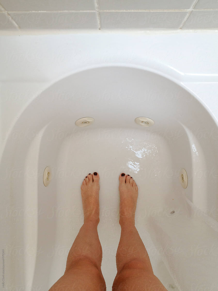 Womans Legs And Feet Standing In A Wet Bathtub By Stocksy