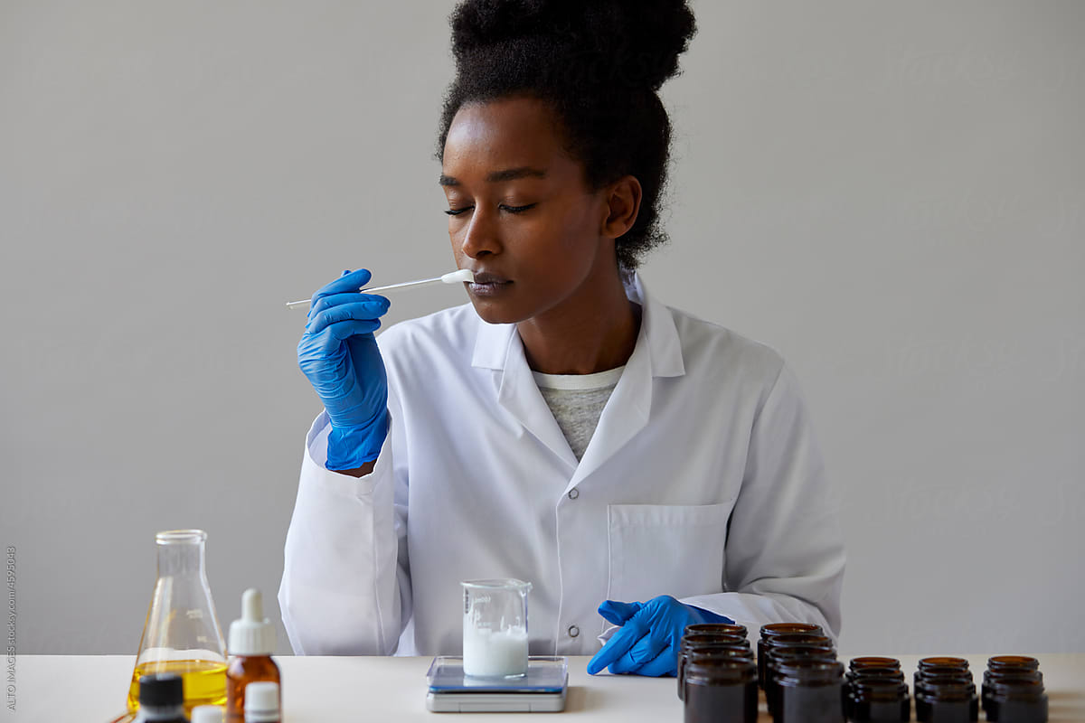 Black pharmacist sniffing natural skincare product