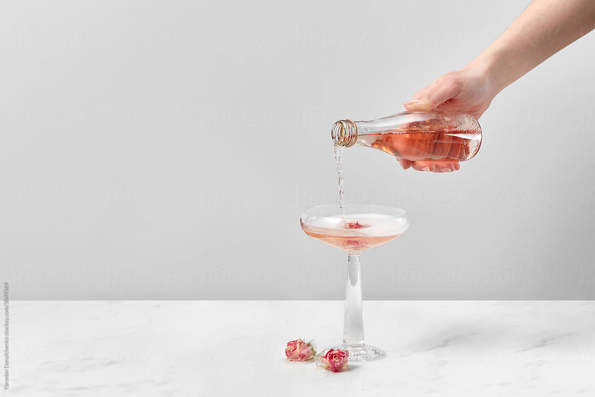 Woman pouring drink in glass with rose