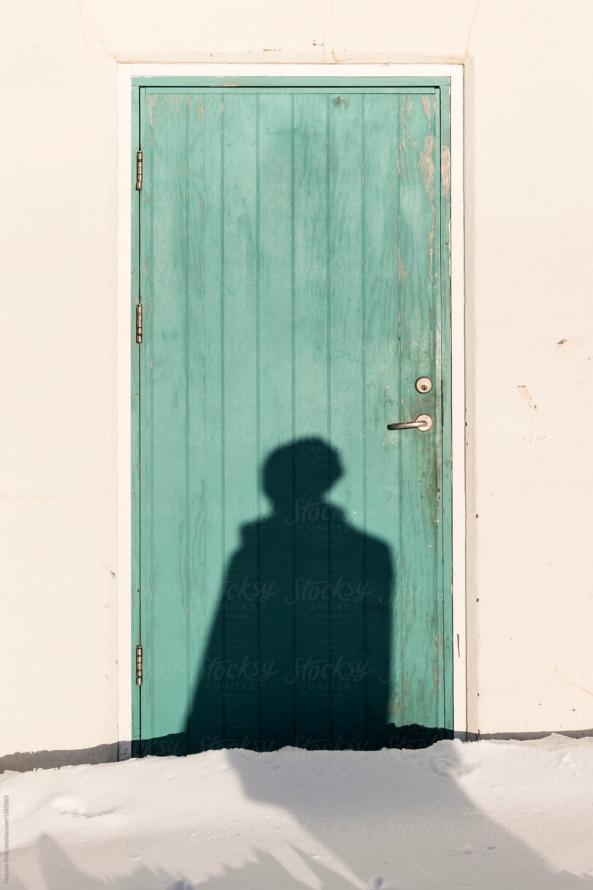 Shadow of a person falls onto a teal wooden door