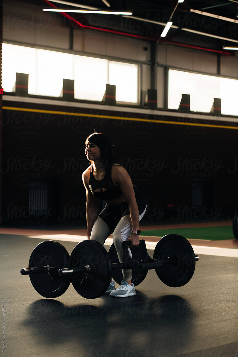 Crossfit athlete - young beautiful woman doing deadlifts with a trap multi grip bar