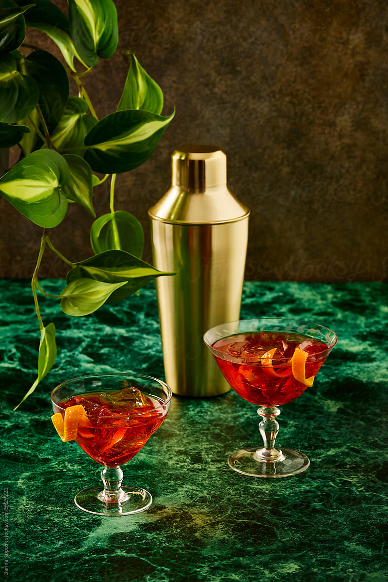 Two Negroni Cocktails with Gold Shaker on Green Marble Tabletop