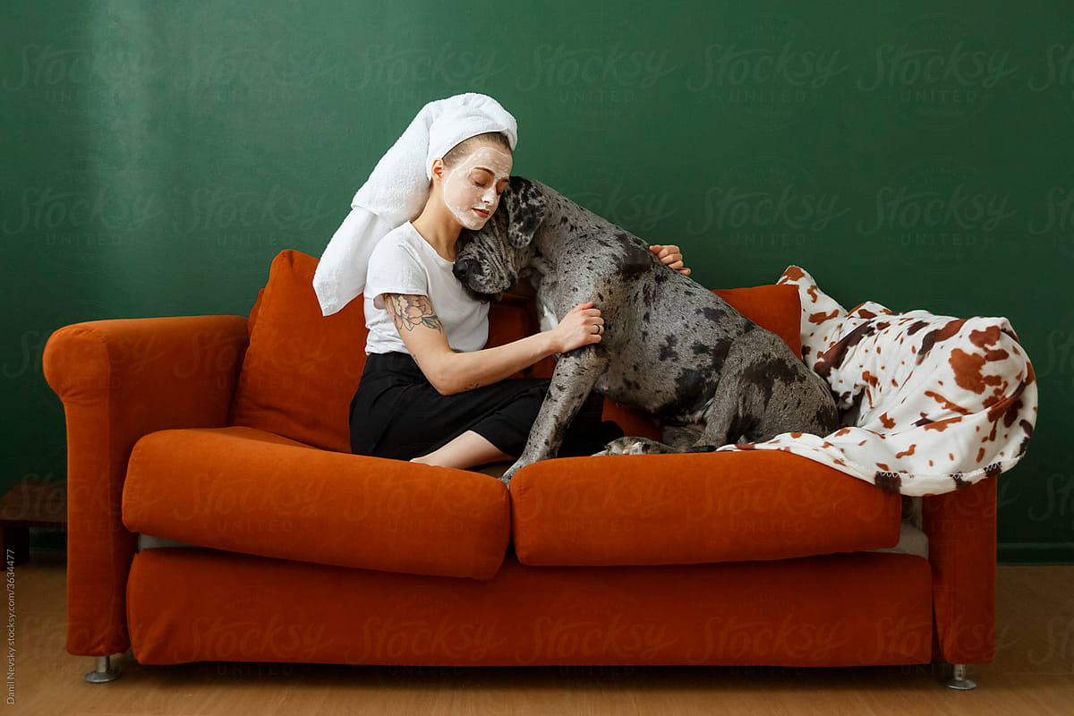 Female owner with mask embracing dog on sofa