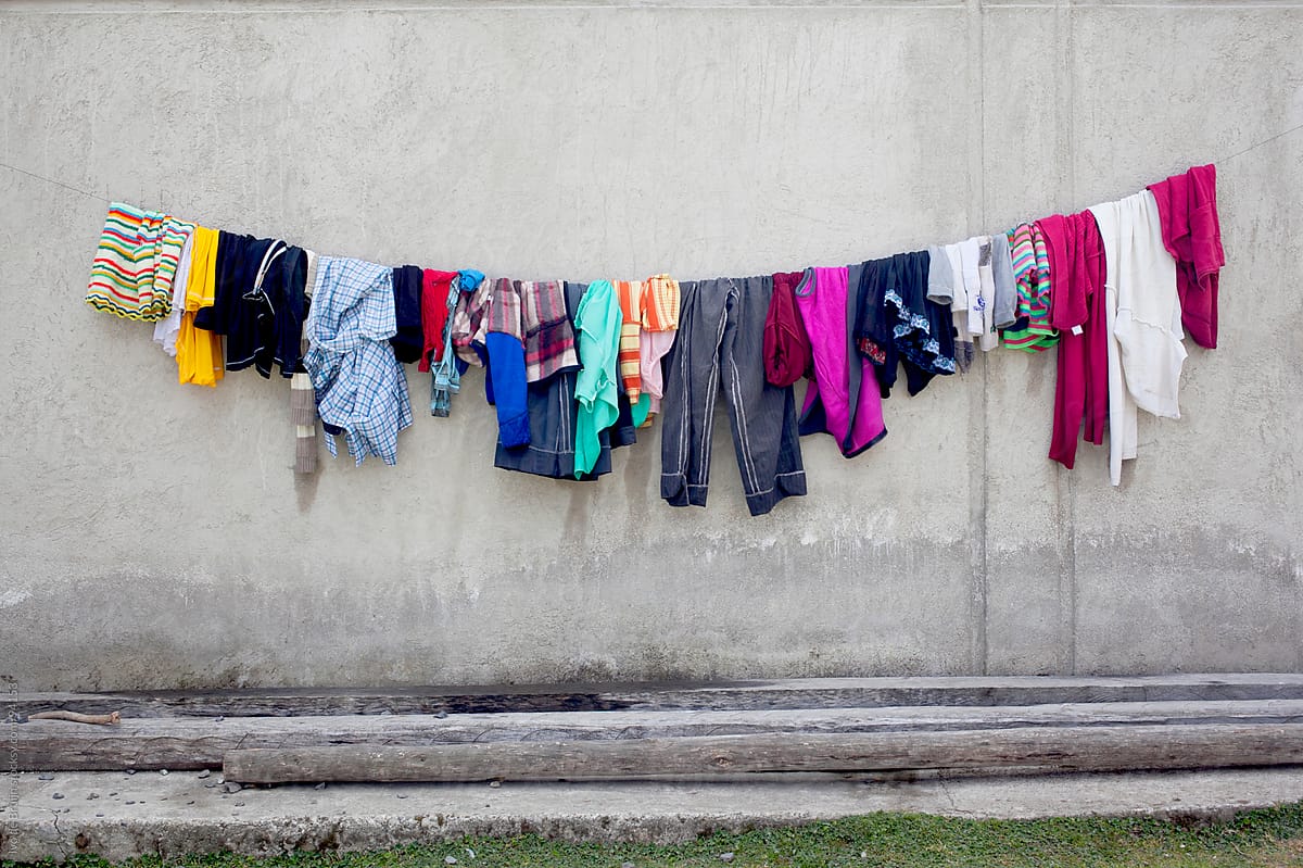 Colourful wet laundry hanging to dry in front of a wall