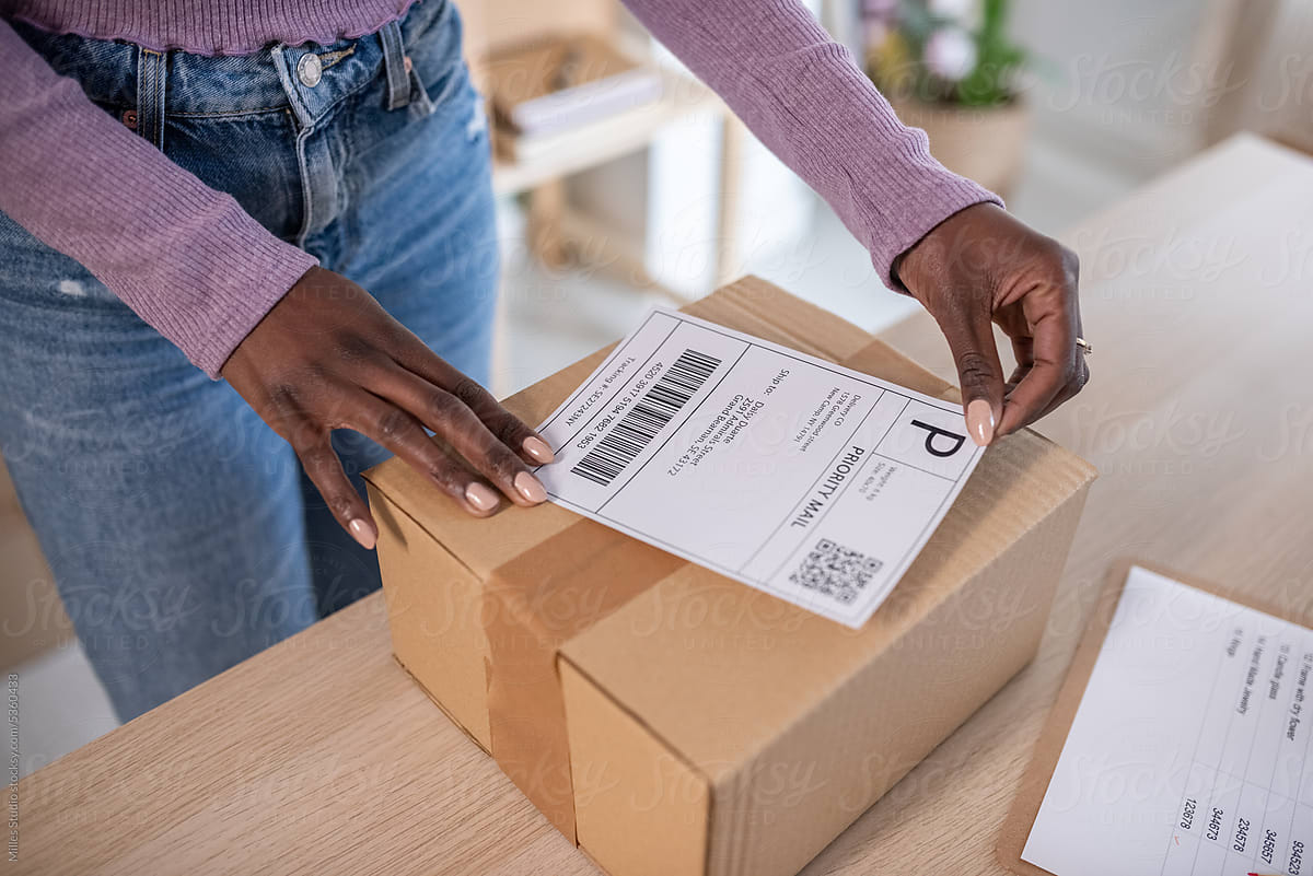 Black woman attaching address label to parcel