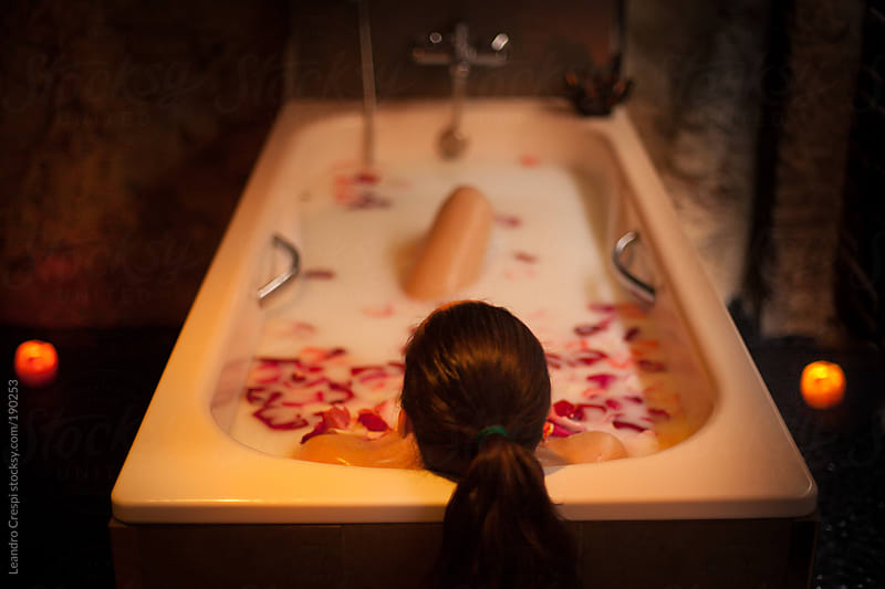 Woman having milk bath with roses in spa