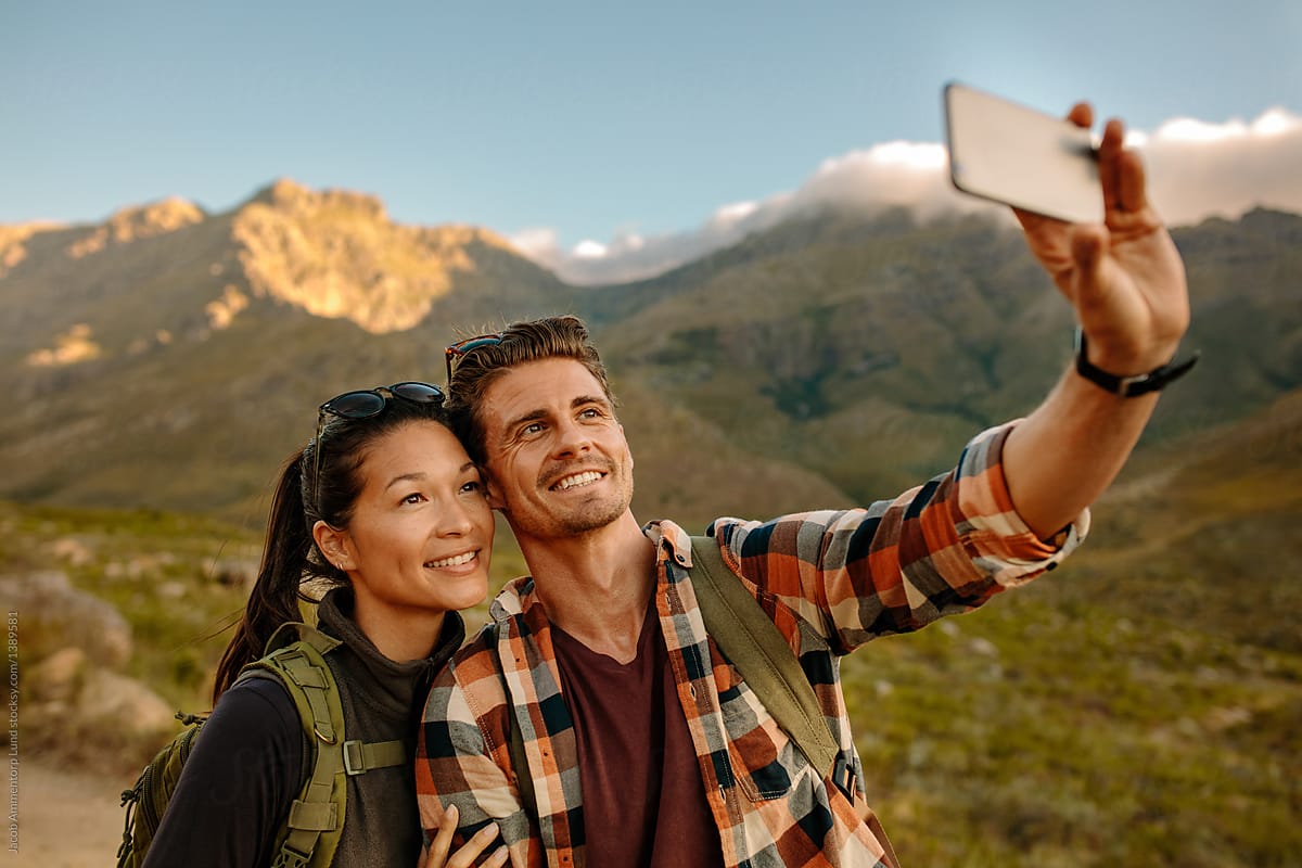 Young couple hiking taking selfie with smart phone