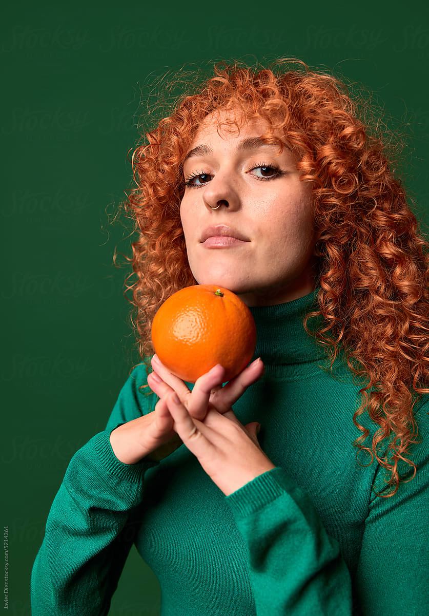 Curly redhead lady with orange behind back