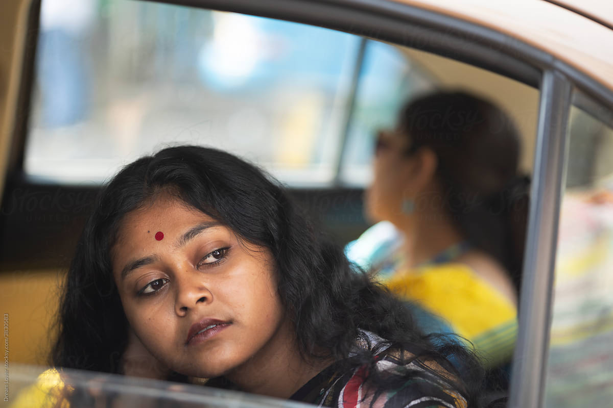 Young Indian woman travelling  in a car looking outwards