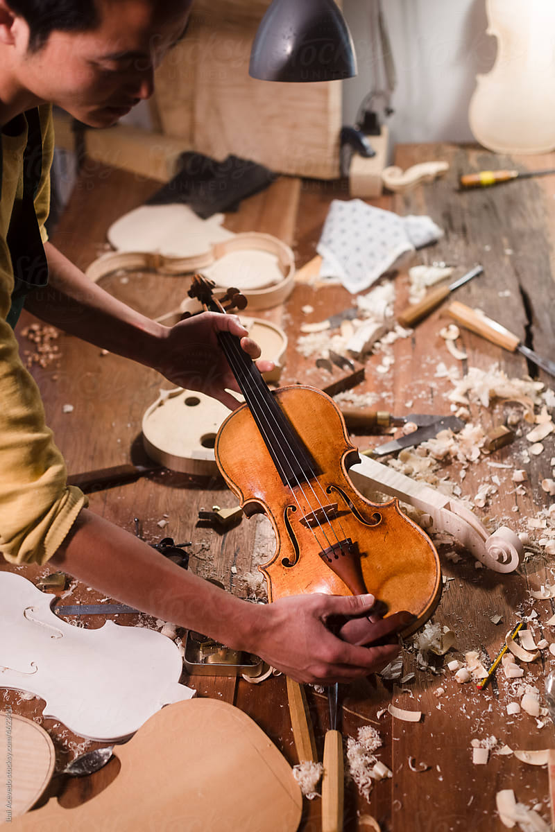Luthier holding violin on workshop table