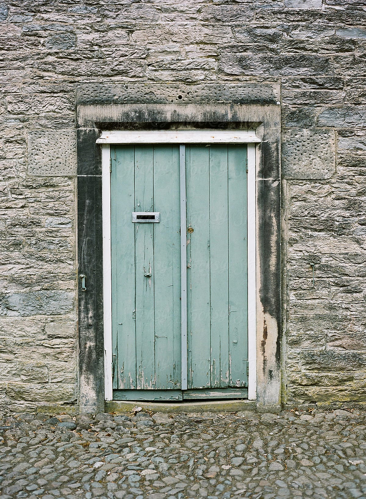 Blue green wooden door in castle wall
