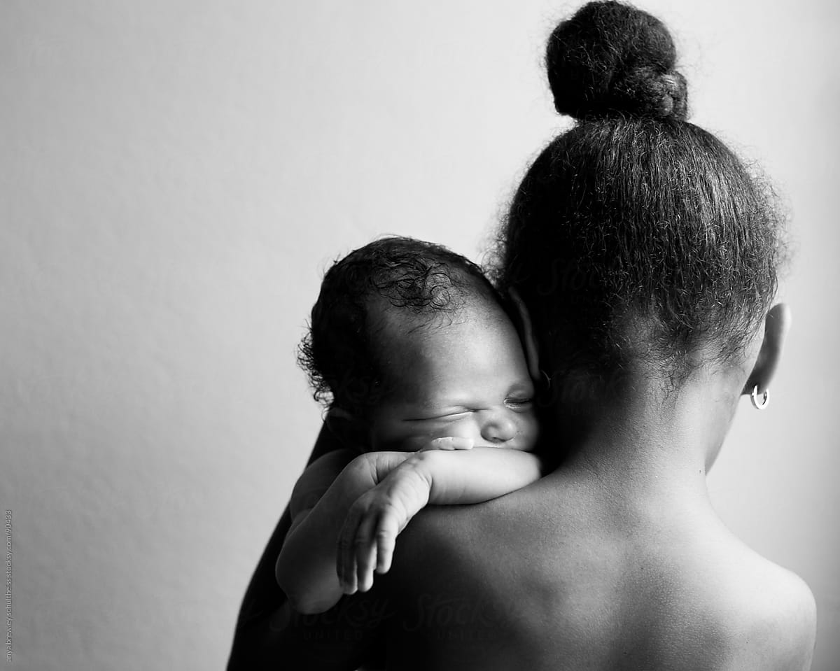 A girl holding her newborn sister over her shoulder