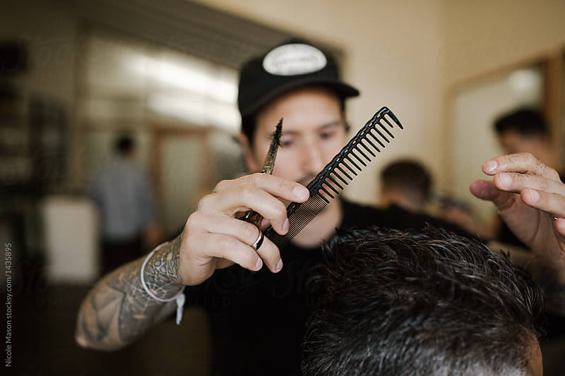 barber holding comb and scissors while cutting hair