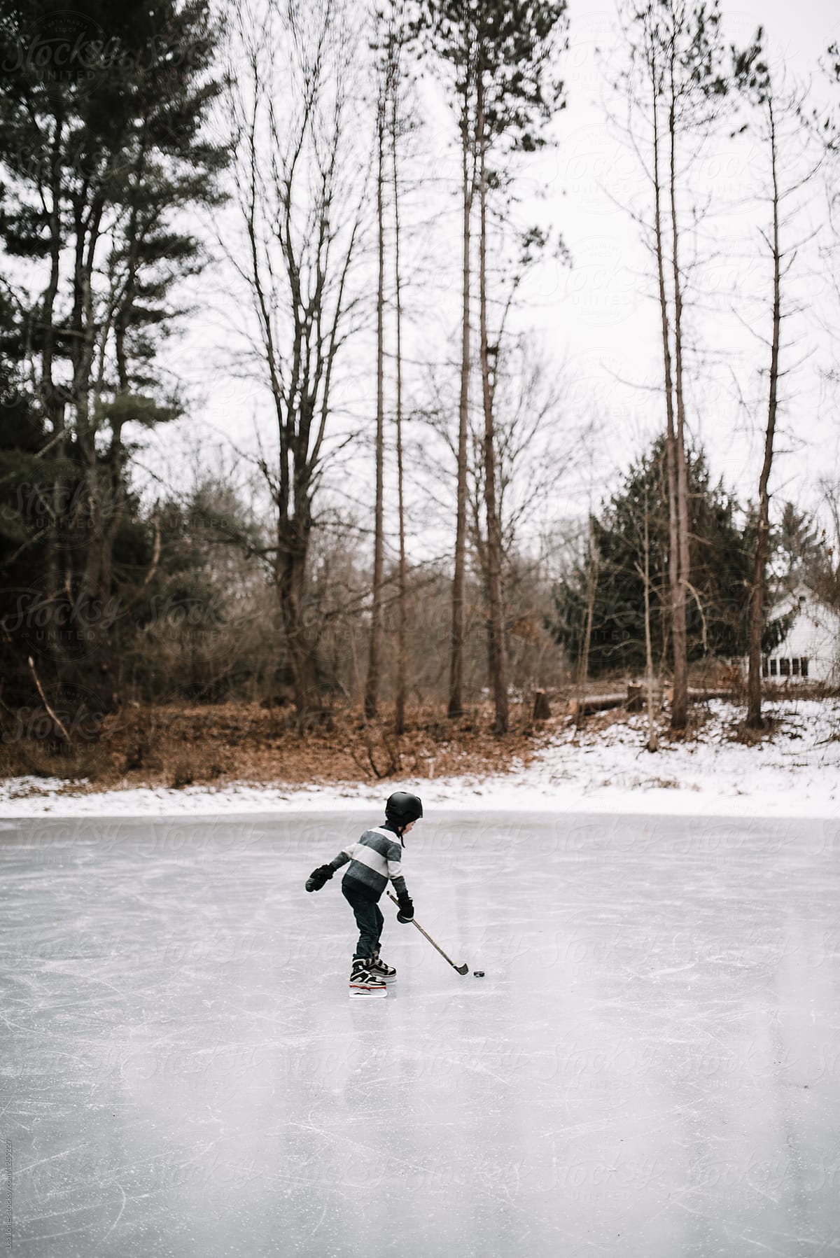 boy playing hockey on frozen pond