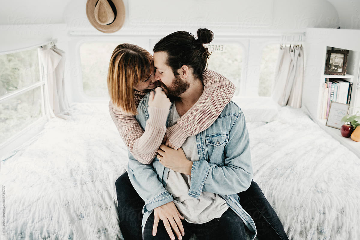 Cute hipster couple cuddling in converted school bus tiny home