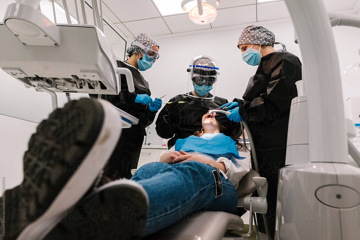 Dentist and assistants treating a patient\'s teeth.