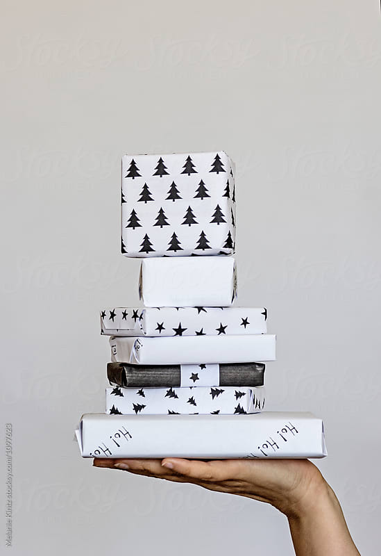 Hand balances a stack of Christmas presents wrapped in black and white
