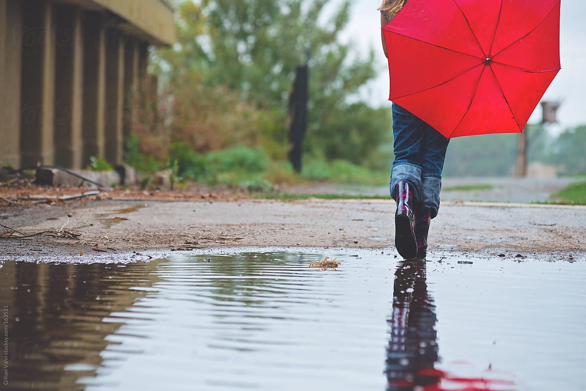 girl walking through puddle with umbrella