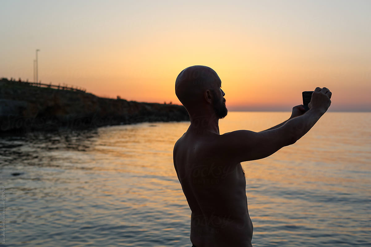 Man taking a selfie during the sunset at a cristal clear beach