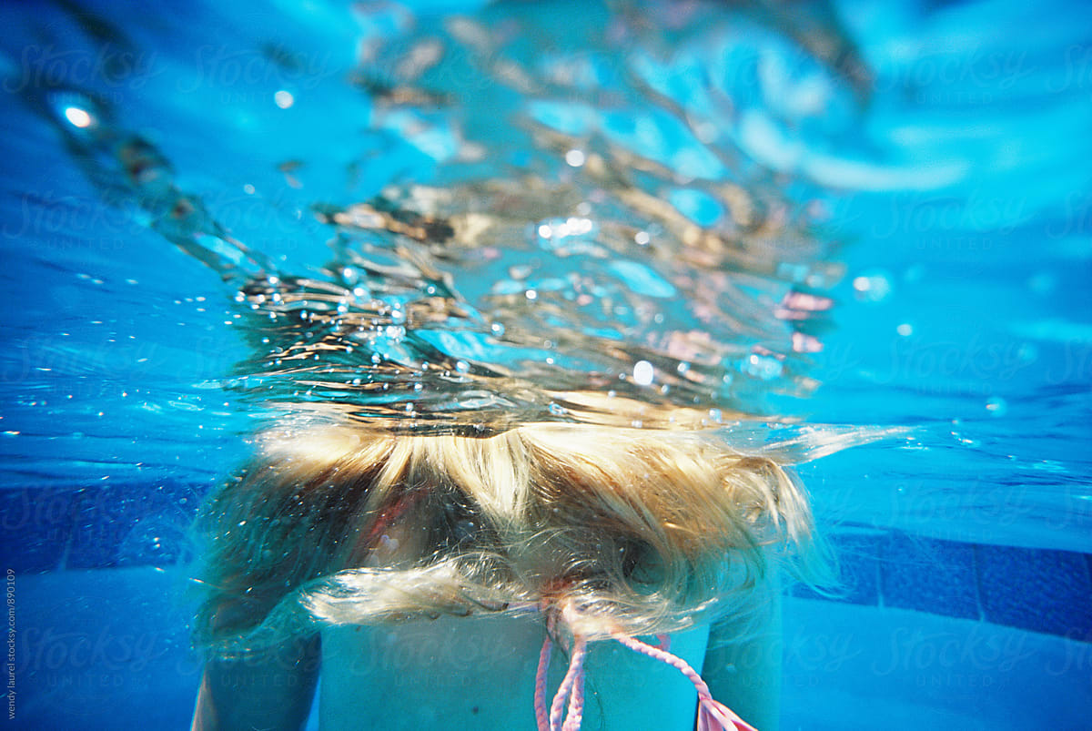 teen girl underwater with hair floating in water in pool