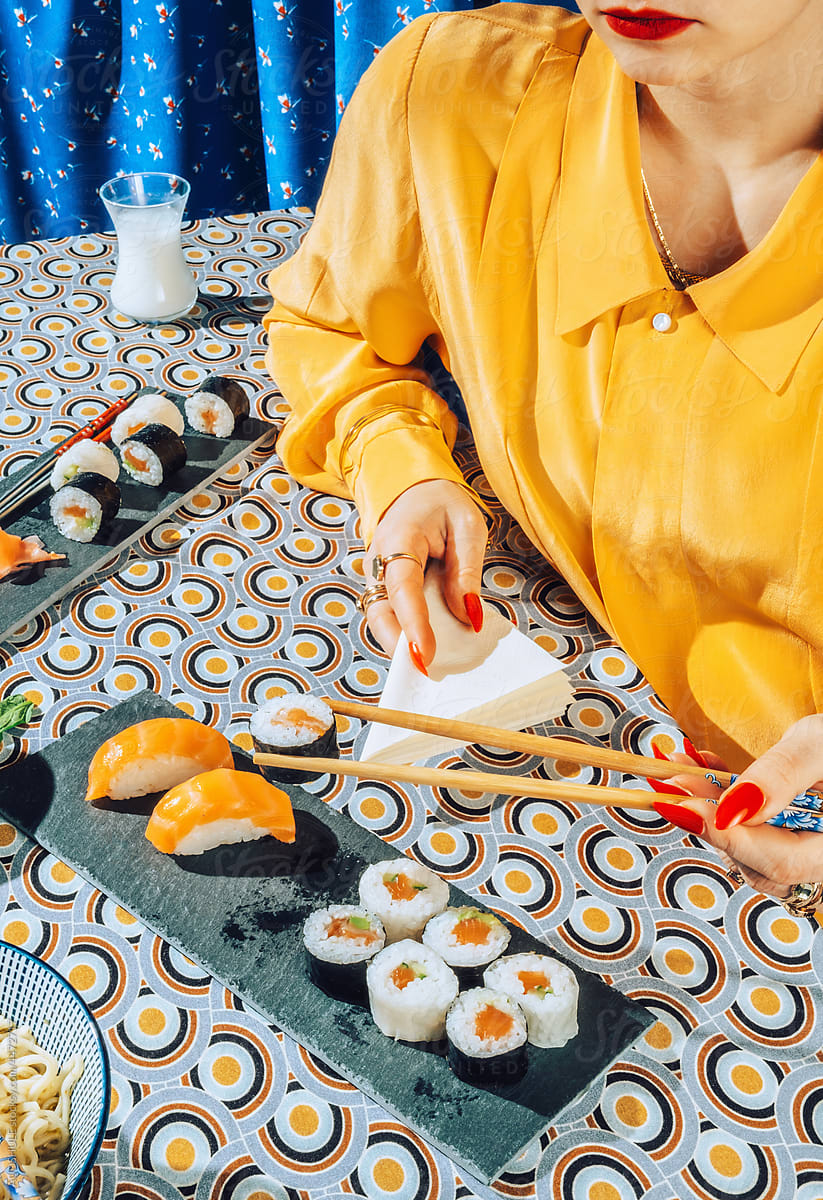Stylish female eating with chopsticks japanese sushi.