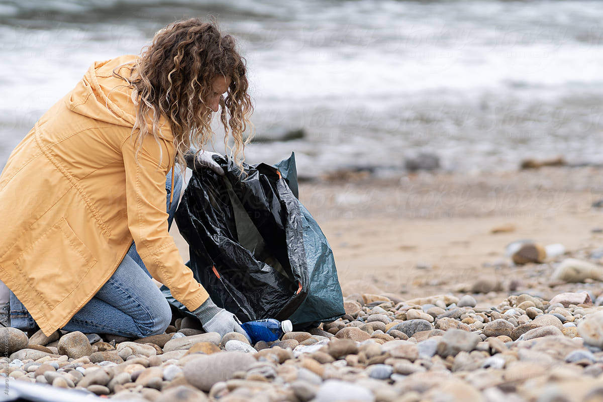 Volunteer picking up plastic at beach.