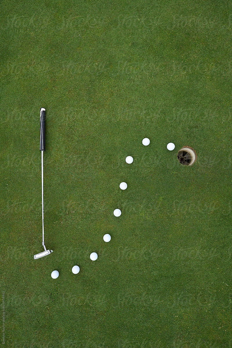Golf putter and balls on putting green