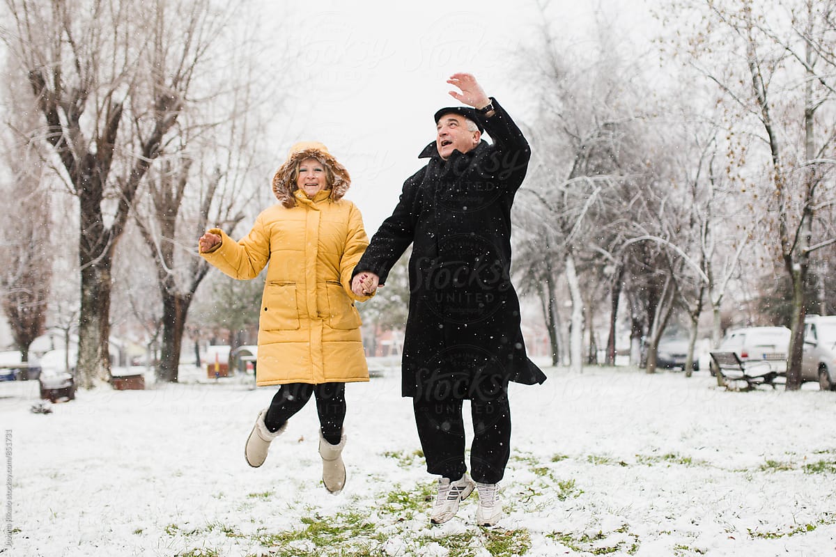 Happy old couple jumping in snow