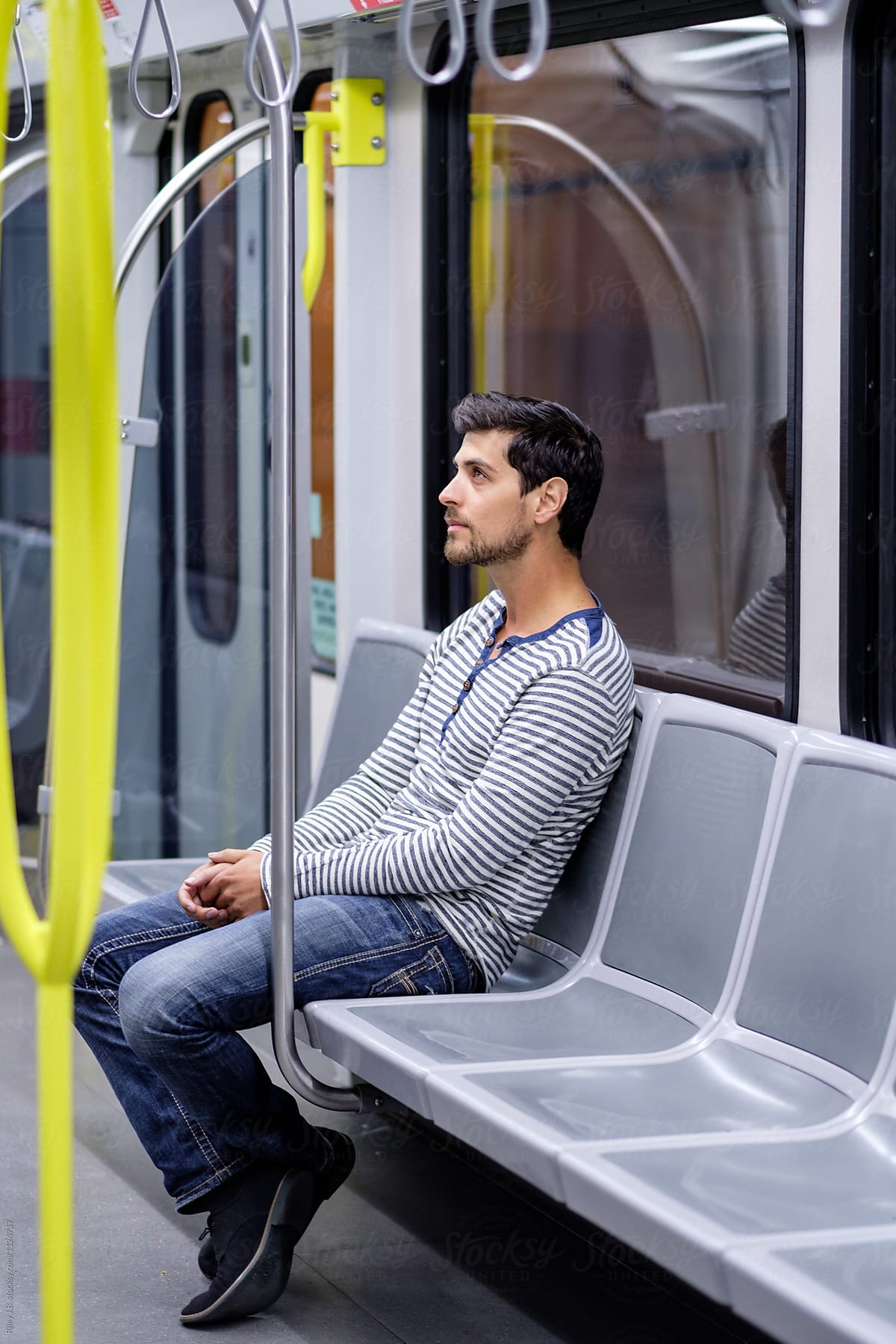 A young man sitting alone while commuting by train