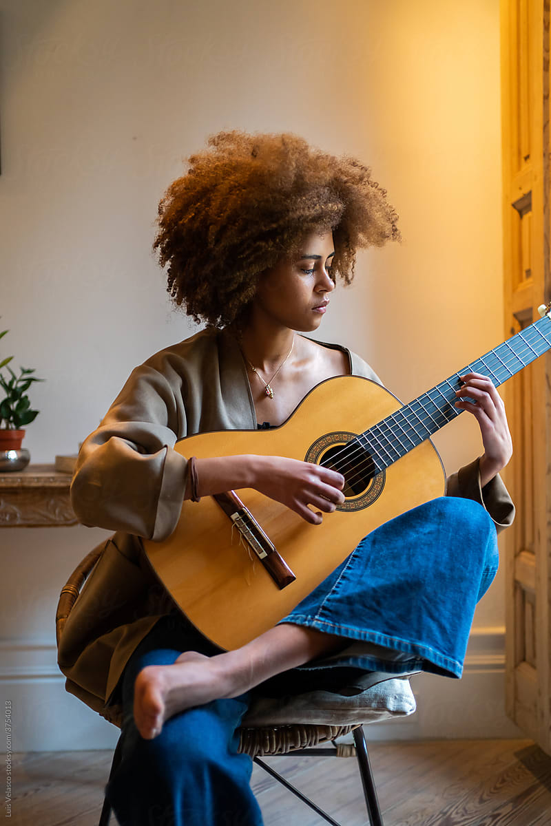 Woman On A Chair Playing The Guitar At Home.