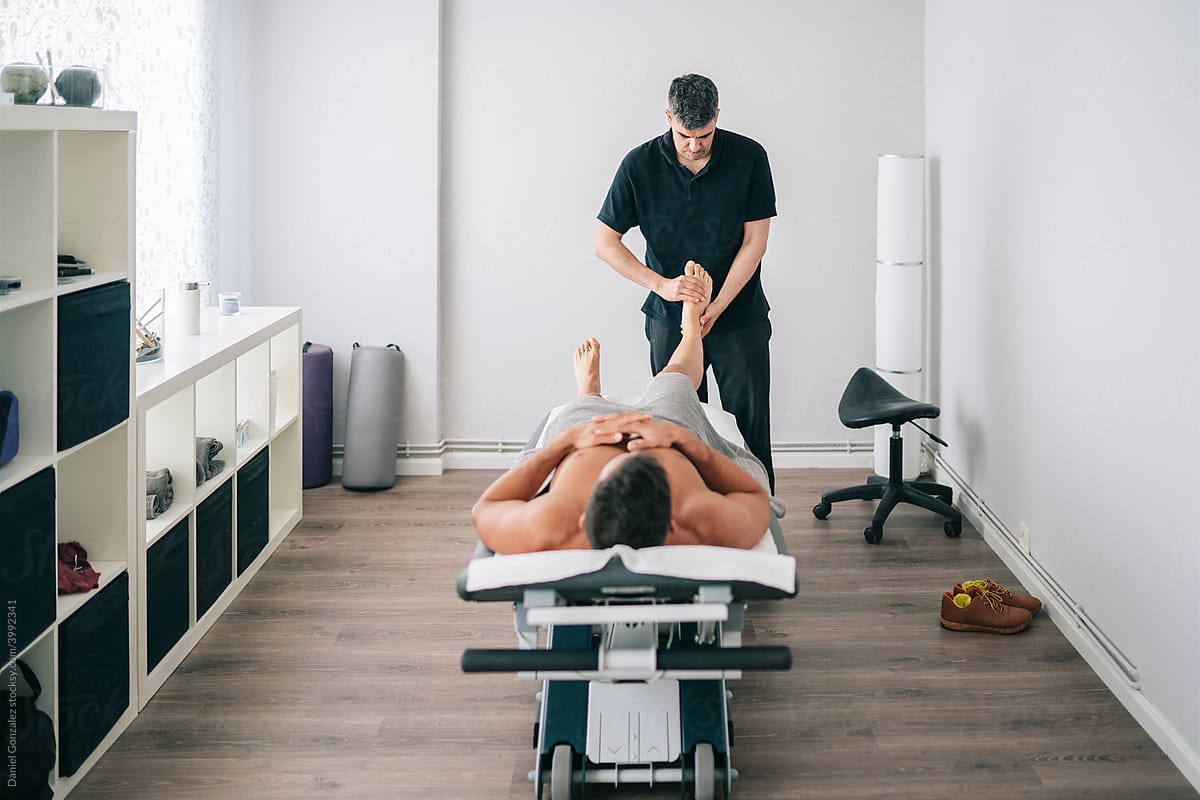 Chiropractor massaging legs of patient in modern clinic