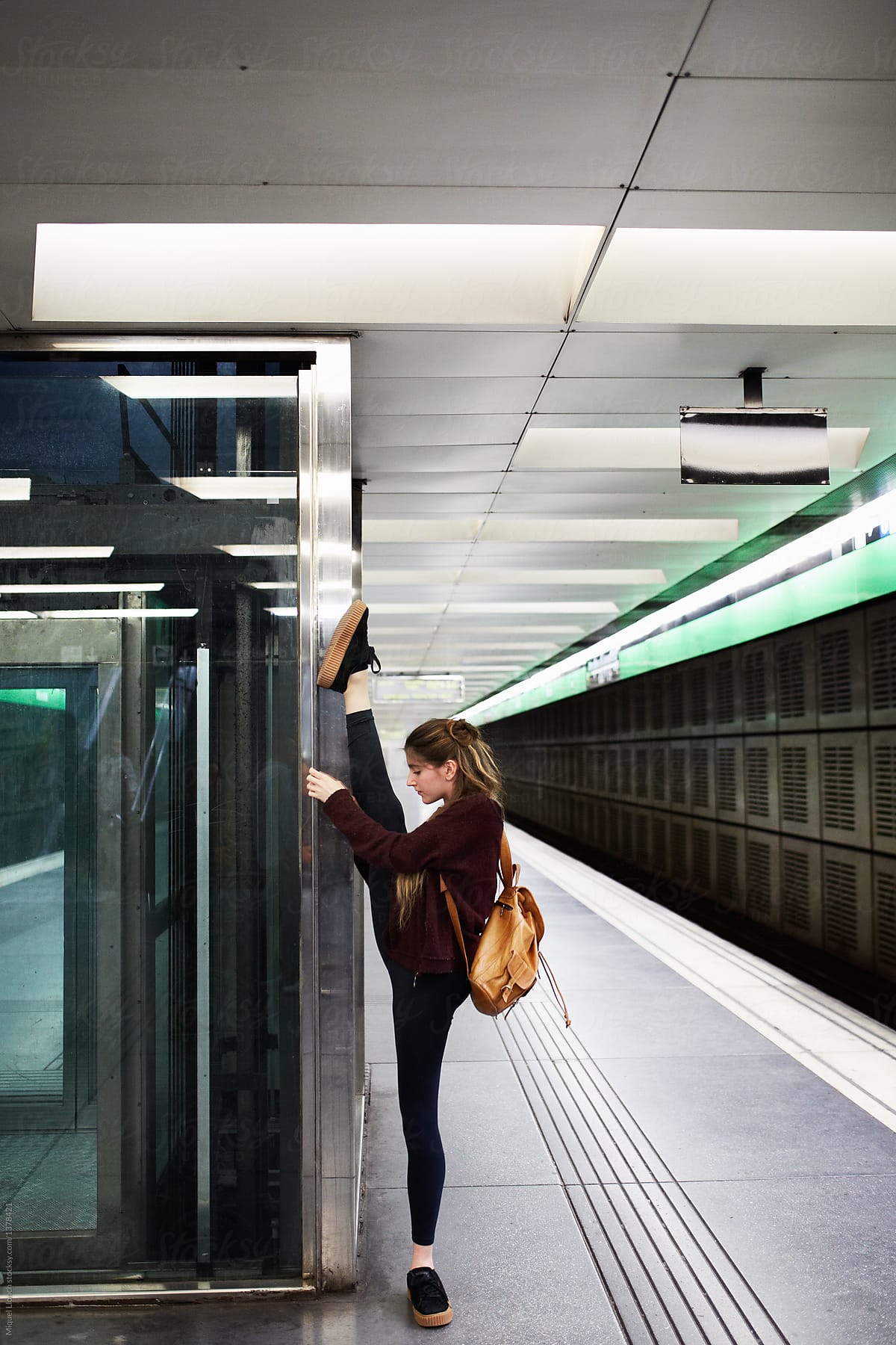 Young woman doing stretch exercises on the subway platform