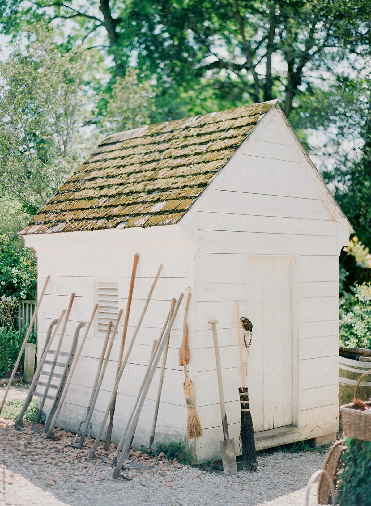 Old white garden shed with antique tools lined up along the side