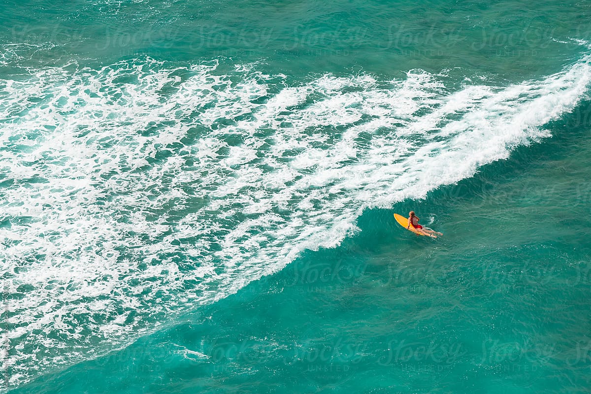 Woman surfing at wild tropical beach