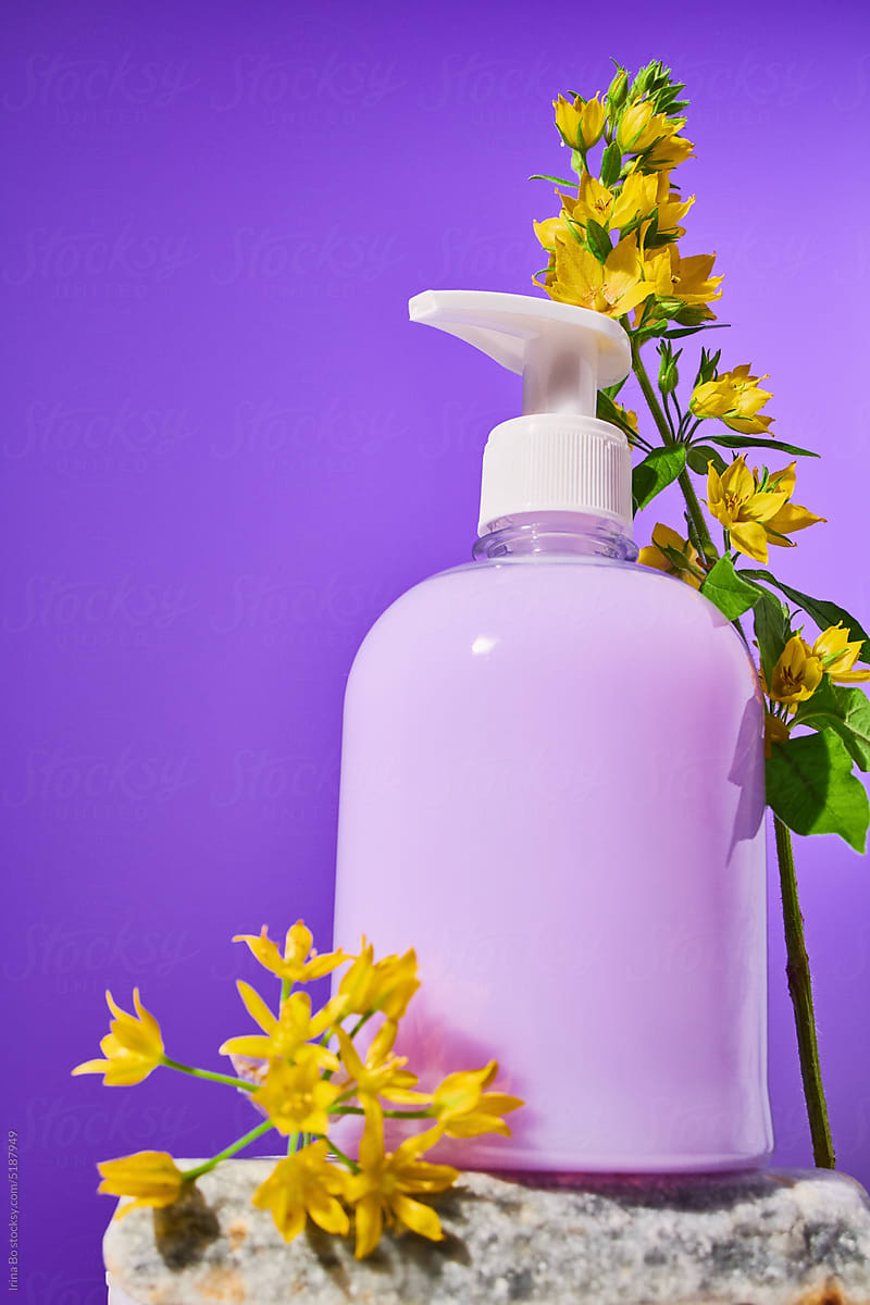 Bottle of liquid purple soap stands in flowers