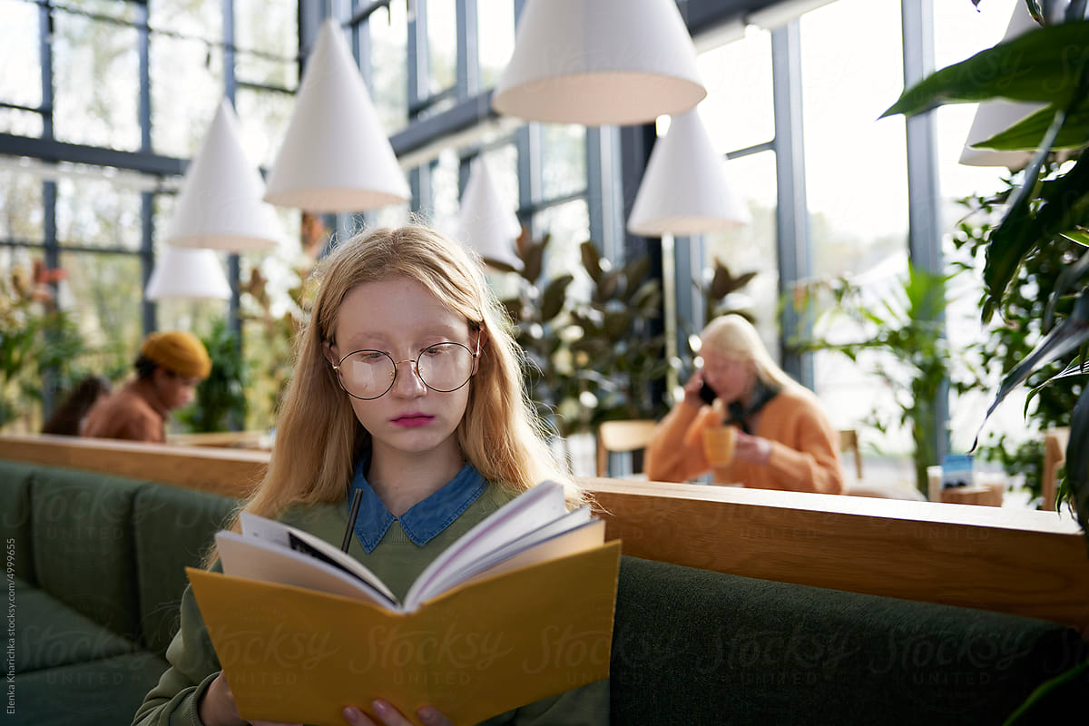 Focused female reading book in city cafeteria