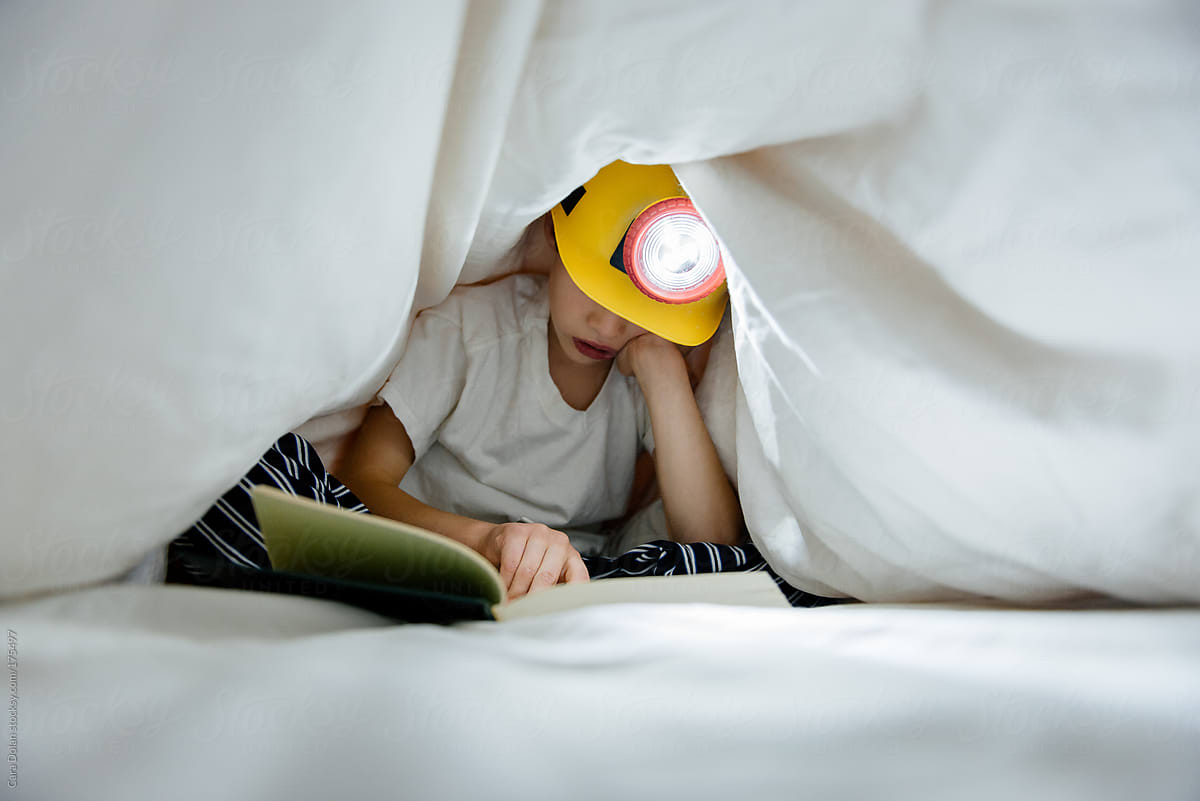 Child Reading in Bed Under the Covers with Headlamp