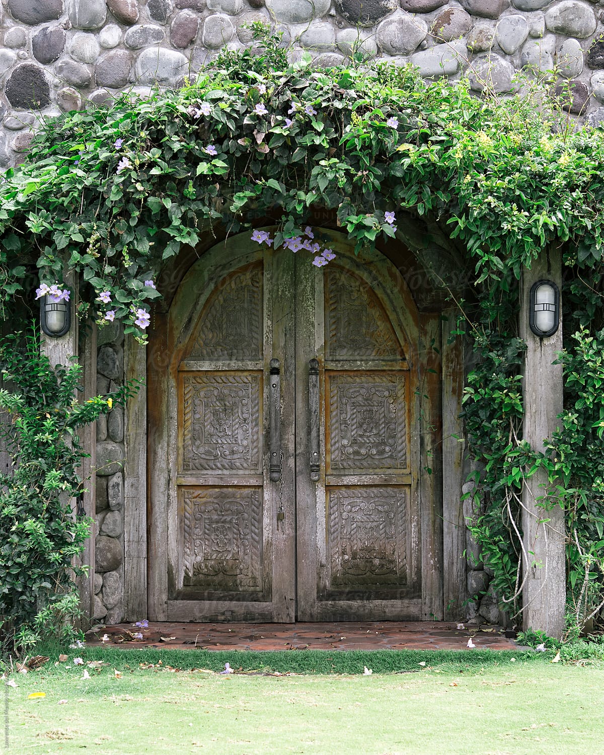 Vines and flowers adorn a wooden door main entrance of a chapel on a hill