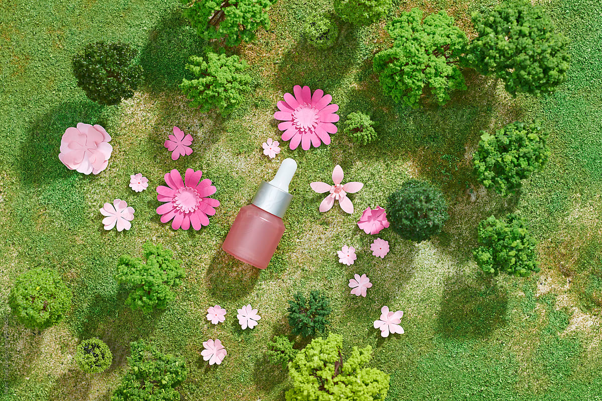 Glass bottle of cosmetic product in forest with grass and green trees