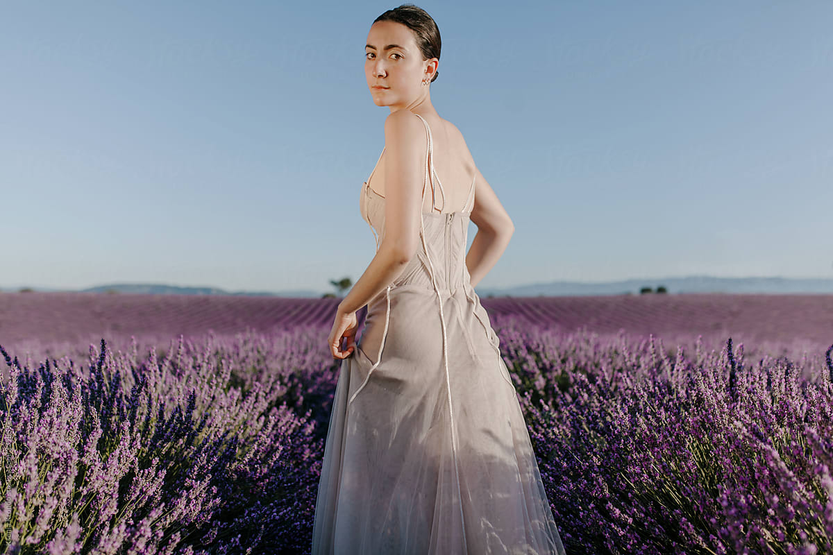 Girl at the lavender field running looking back brunette in long dress
