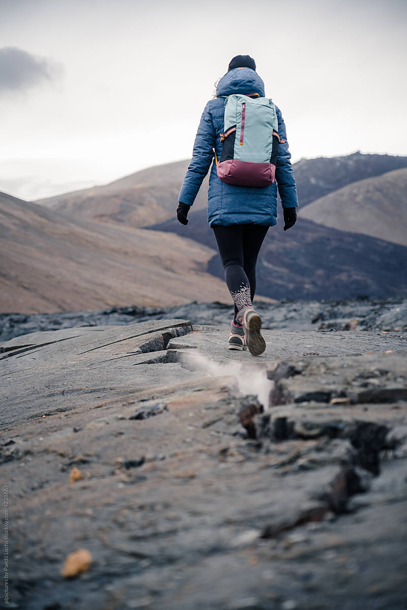 Girl walking along crack in lava field.